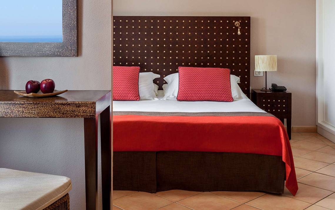 Ein Hotelzimmer von Seaside Sandy Beach mit einem Bett, zwei roten Kissen und einer roten Bettdecke.