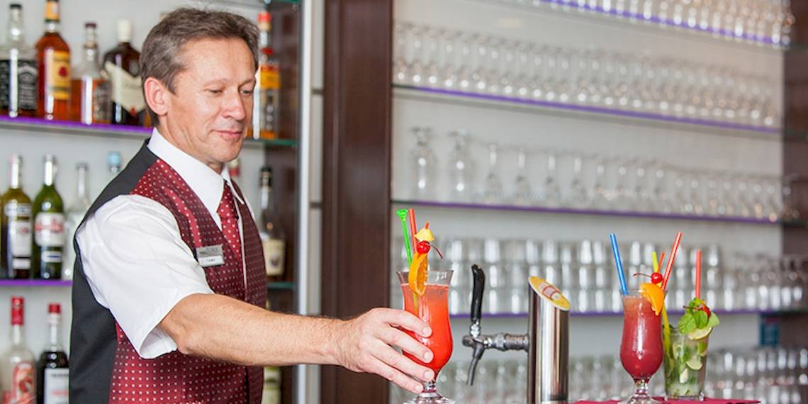 Ein Barkeeper im Zora Hotel bereitet Cocktails hinter der Bar zu.