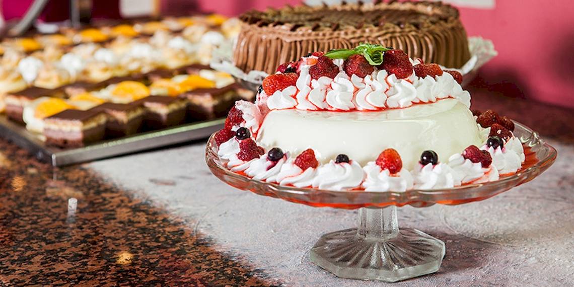 Verschiedene Desserts im Zora Hotel auf einer Glasplatte serviert, einschließlich einer Torte mit Früchten und Sahne.