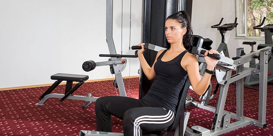 Eine Frau trainiert im Fitnessstudio des Zora Hotels mit Gewichten.