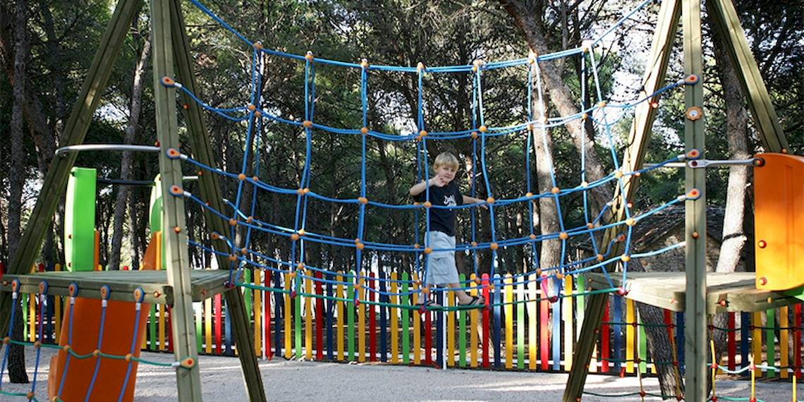 Ein junger Junge klettert an einem Netz in einem Spielplatz im Freien im Zora Hotel.