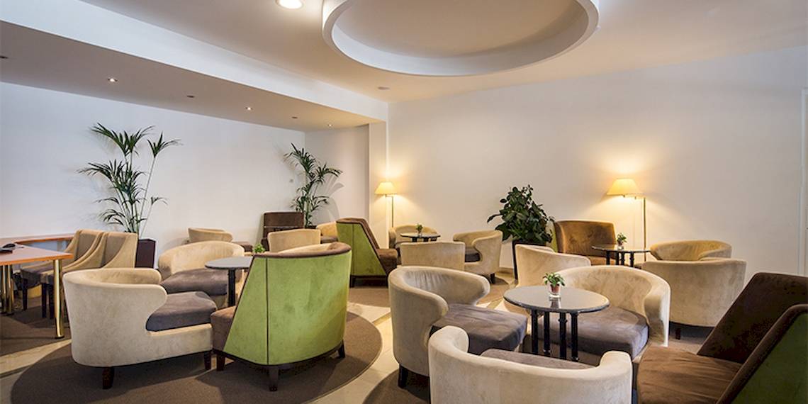 Lobby des Zora Hotels mit vielen Sesseln und Tischen, umgeben von Pflanzen und Lampen.