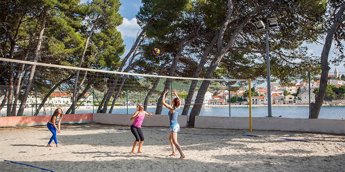 Drei Frauen spielen Volleyball auf dem Strand vor dem Zora Hotel.