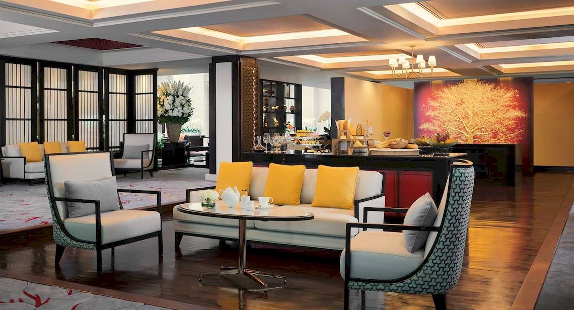 Lobby des Anantara Riverside Bangkok Resort mit Sofas, Tischen und Dekoration.