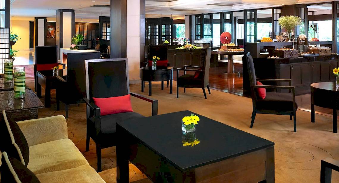 Lobby des Anantara Riverside Bangkok Resorts mit modernen Möbeln und Blumenarrangements.