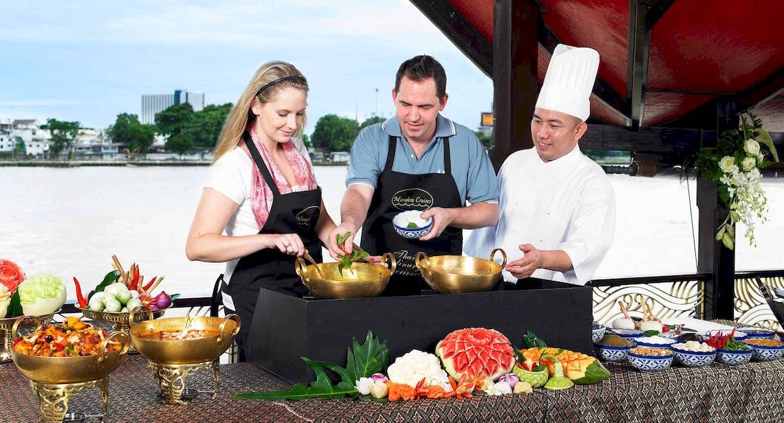 Ein Kochkurs auf dem Boot des Anantara Riverside Bangkok Resort mit Gästen und Köchen.