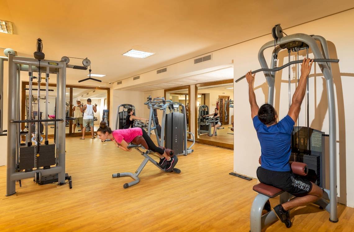 Fitnessbereich im Ulysse Djerba Thalasso & Spa mit verschiedenen Geräten und Personen beim Training.