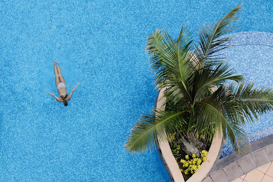 Luftaufnahme einer Person, die im Schwimmbad des Mövenpick Hotels Jumeirah Beach schwimmt.