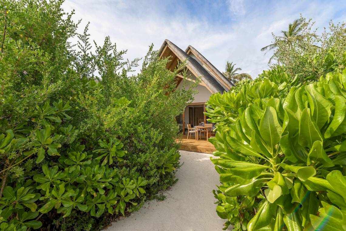 Außenansicht des Fushifaru Maldives Hotels mit einer kleinen Hütte und einem Tisch im Freien.