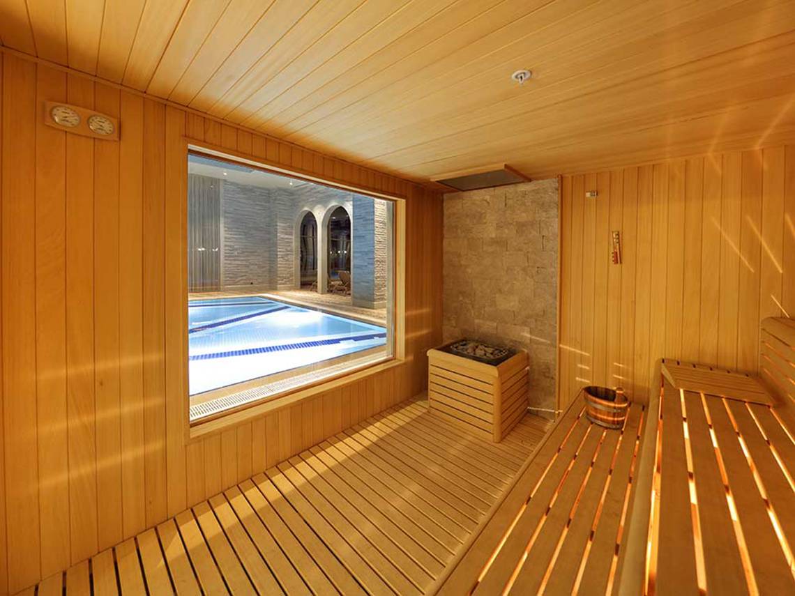 Eine geräumige Sauna mit Holzwänden und einem Fenster, das einen Pool zeigt.