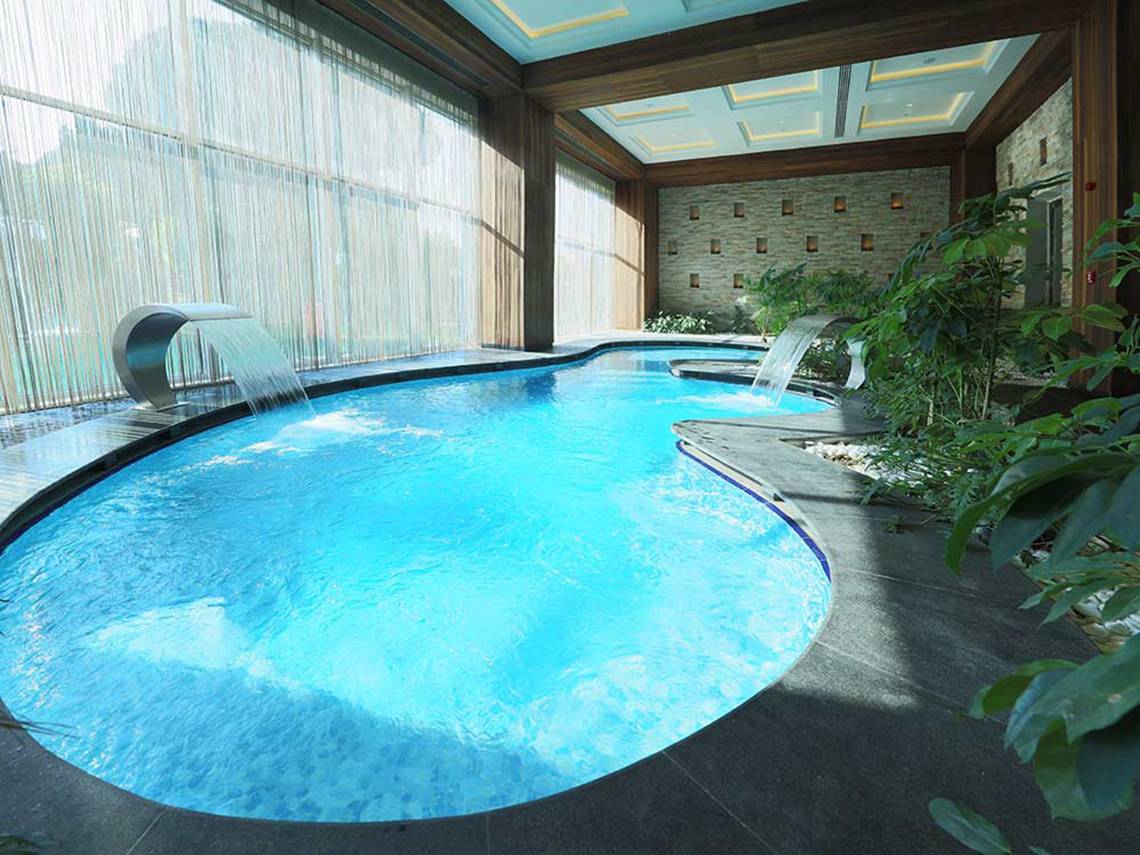 Innenpool des Sueno Hotels Deluxe Belek mit Wasserfall und Pflanzen.