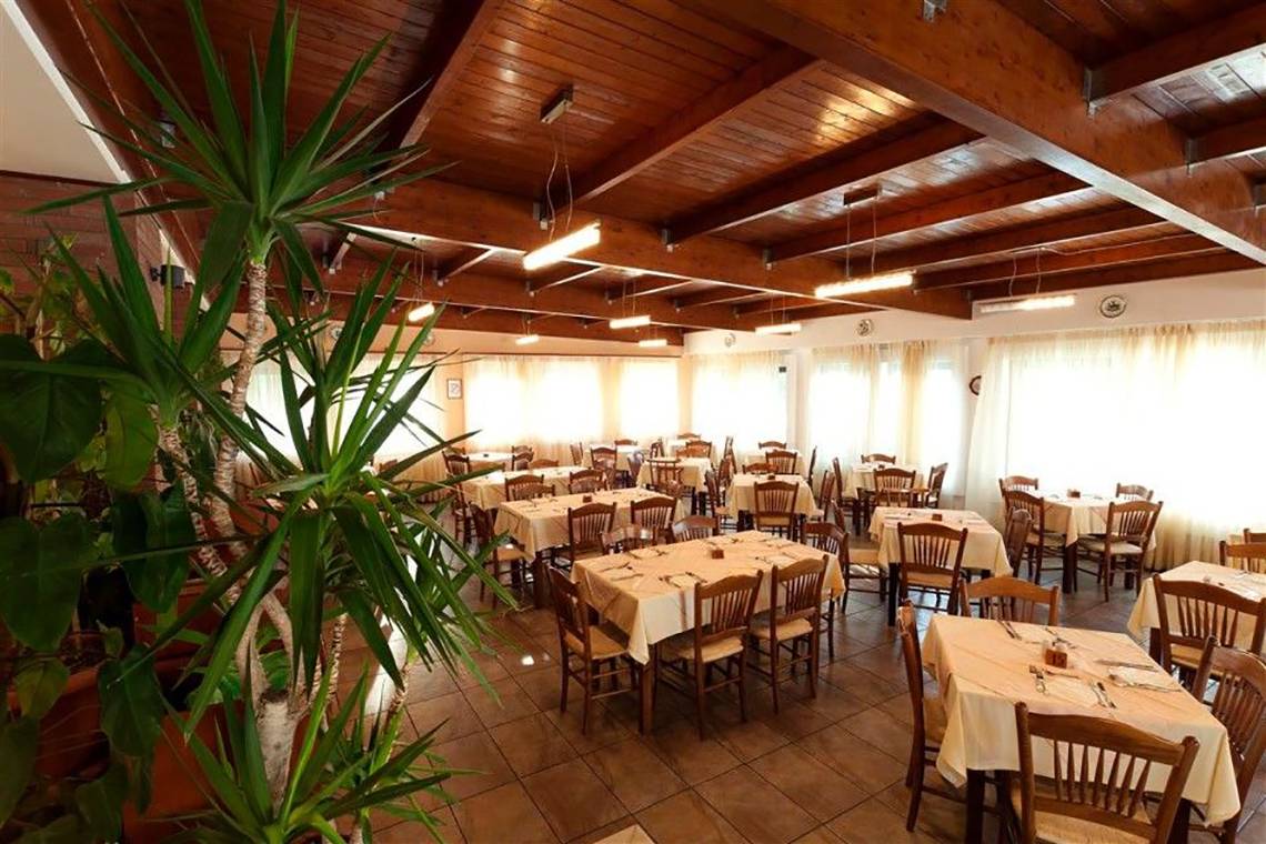 Innenansicht des Restaurants im Atlantica Marmari Beach Hotel mit gedeckten Tischen und Stühlen.