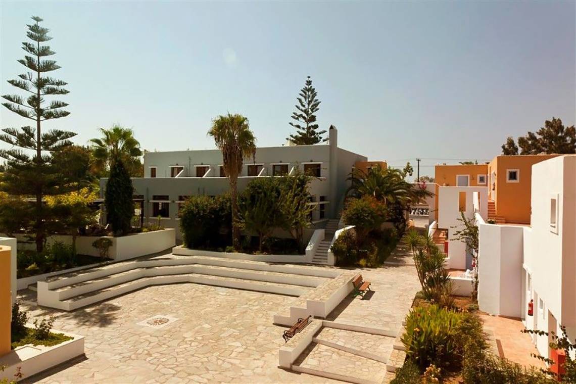 Außenbereich des Atlantica Marmari Beach Hotels mit Gebäuden, Treppen und Pflanzen.