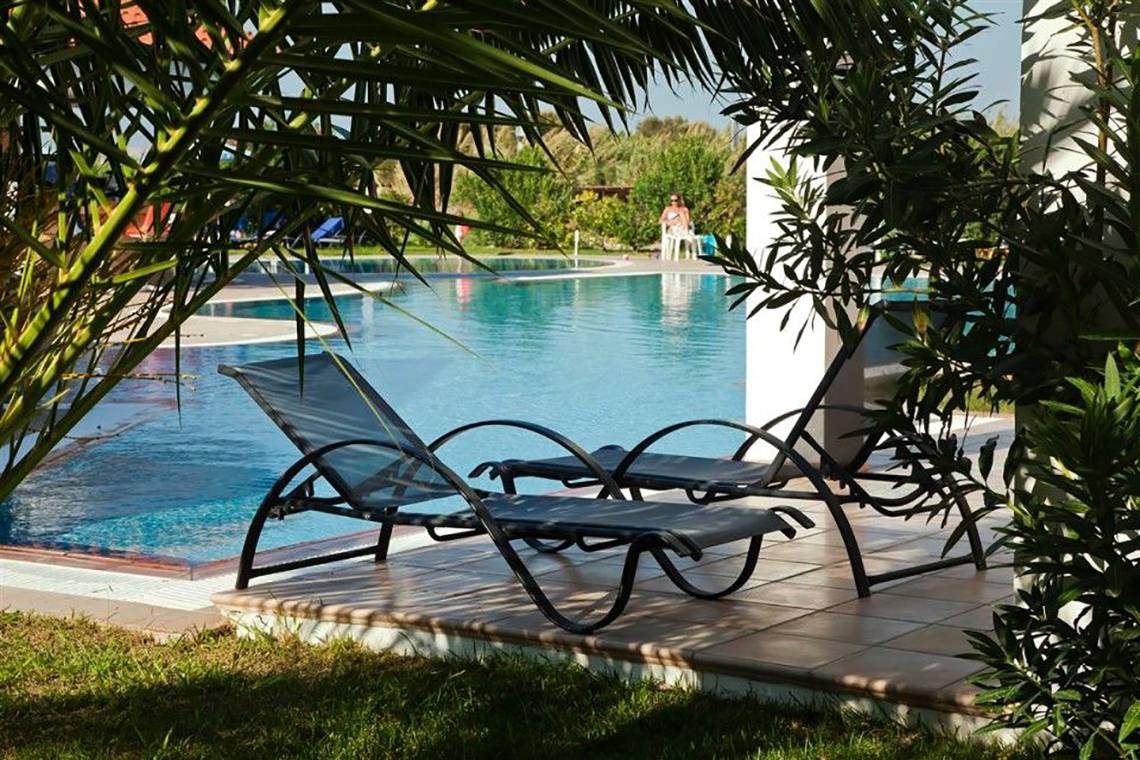 Zwei schwarze Liegestühle am Poolrand des Atlantica Marmari Beach Hotels