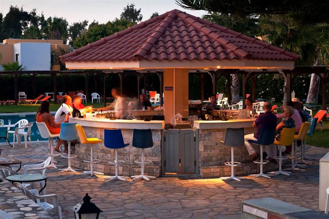 Gäste sitzen an der Bar im Atlantica Marmari Beach Hotel mit Blick auf den Pool.
