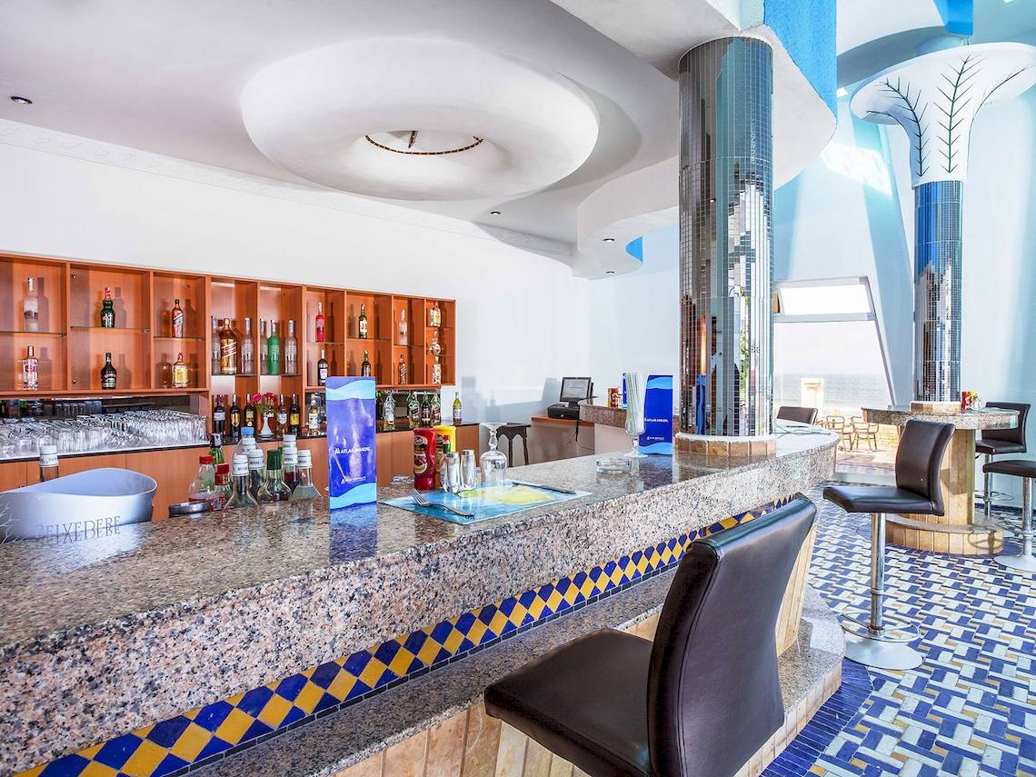 Die Bar im Atlas Amadil Beach Hotel mit Granittheke und blau-gelbem Bodenmuster.
