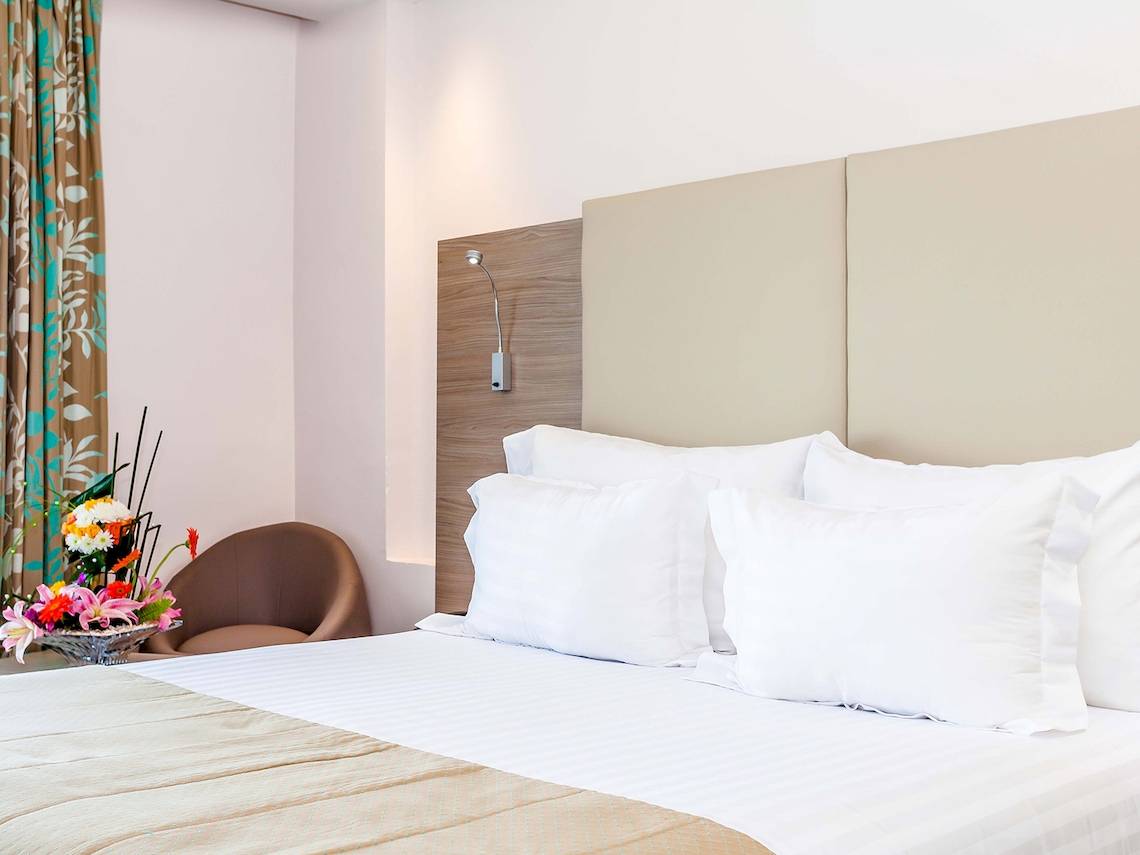 Atlas Amadil Beach Hotel Schlafzimmer mit Bett, Kissen, Blumen und Stuhl