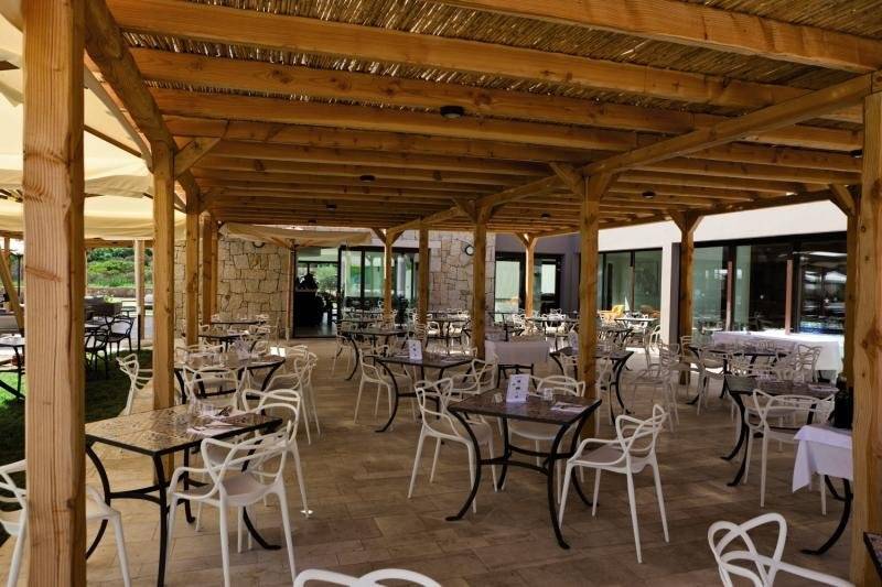 Außenbereich des Baglioni Resort Sardinia mit überdachter Terrasse und Tischen