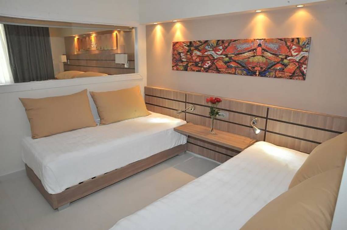 Doppelbettzimmer im Atlantica Holiday Village Kos mit modernen Möbeln und Kunstwerk an der Wand.