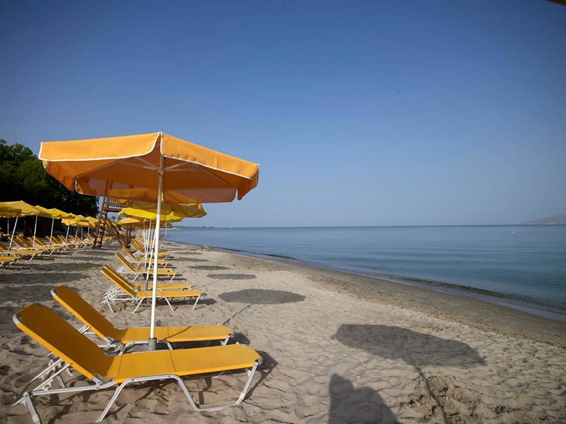 Strand mit gelben Sonnenliegen und Sonnenschirmen am Atlantica Holiday Village Kos