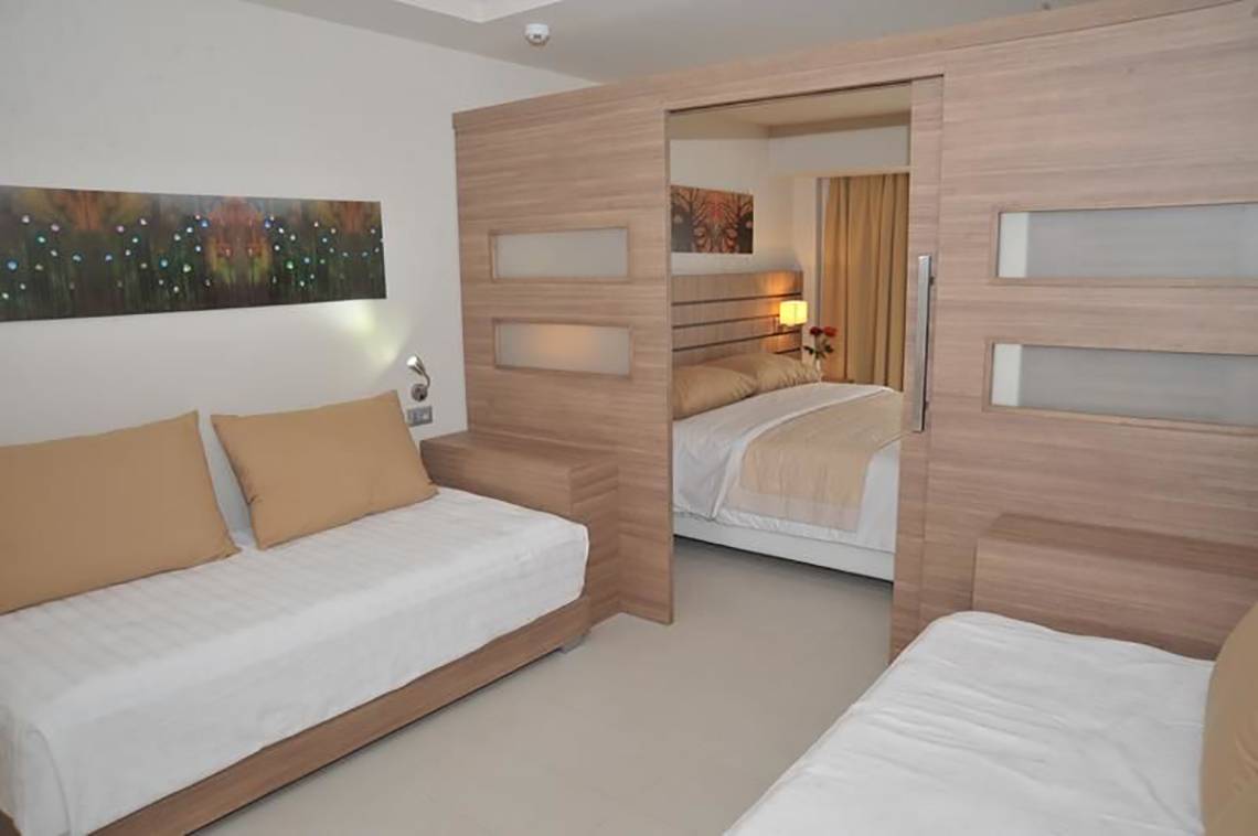 Schlafzimmer im Atlantica Holiday Village Kos mit zwei Einzelbetten und einem Doppelbett.