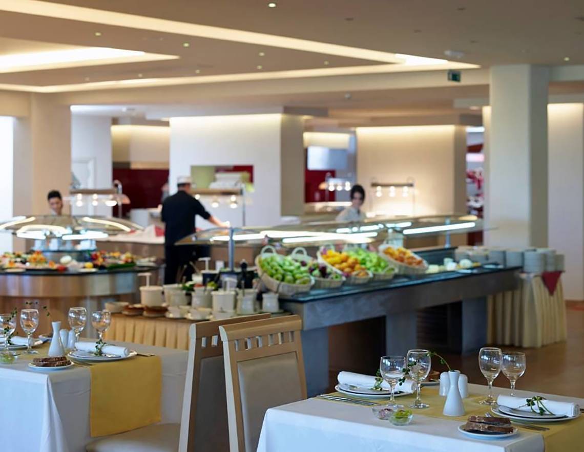 Buffetbereich im Atlantica Holiday Village Kos Hotel mit gedeckten Tischen und Buffet mit verschiedenen Speisen.