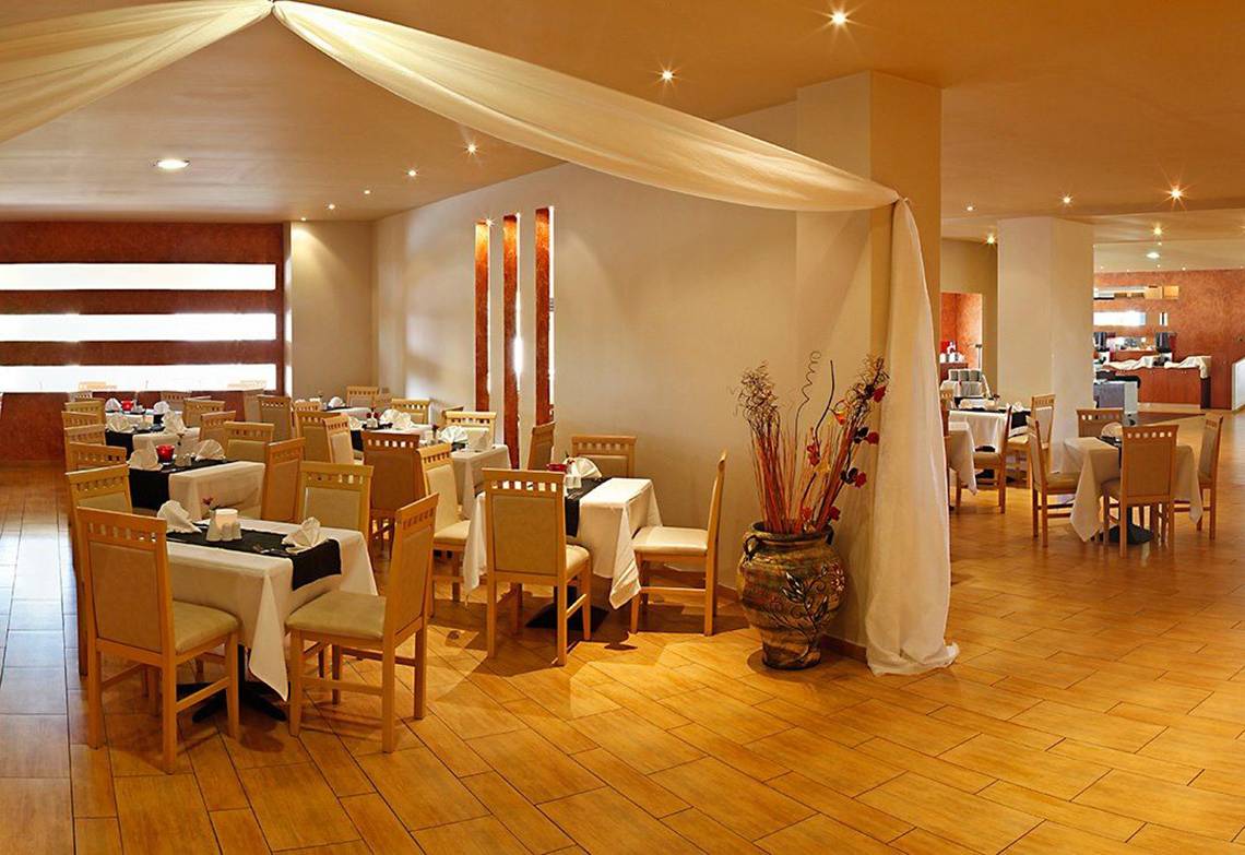 Innenbereich des Restaurants im Atlantica Holiday Village Kos mit gedeckten Tischen und Stühlen.