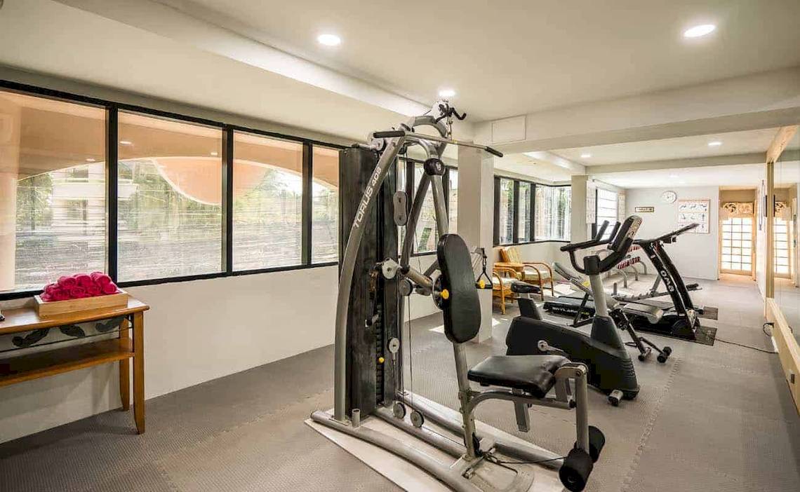 Fitnessraum im Chaba Samui Resort mit mehreren Trainingsgeräten und großen Fenstern.