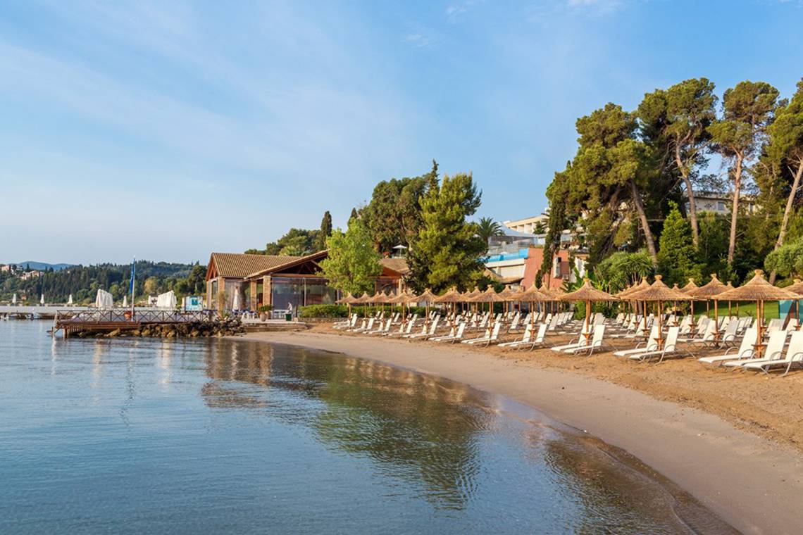 Strand von Kontokali Bay Resort & Spa mit vielen Sonnenliegen und Sonnenschirmen.