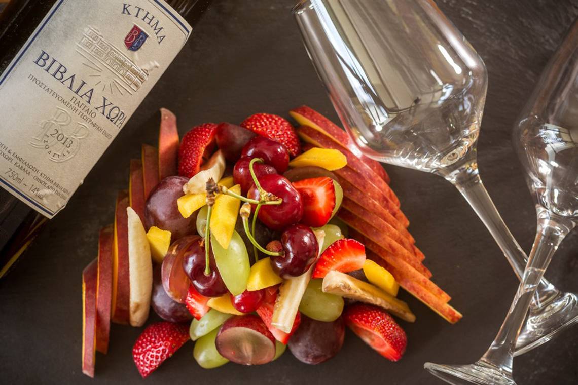 Obstsalat mit Weingläsern und einer Flasche Wein auf schwarzem Hintergrund