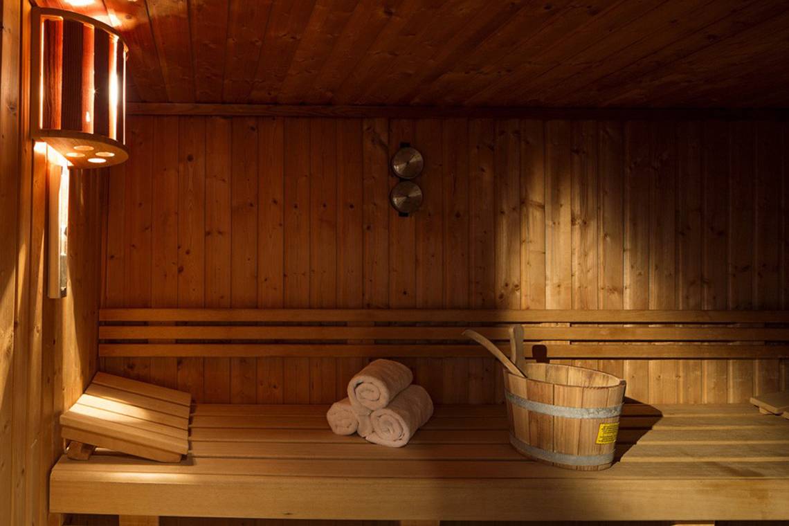 Eine Holzsauna mit einer Holzbank, einem Eimer und Handtüchern.