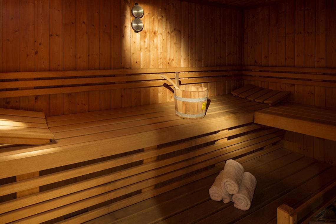 Eine geräumige, helle Sauna im Hotel Kontokali Bay Resort & Spa mit Holzbänken und einem Eimer.