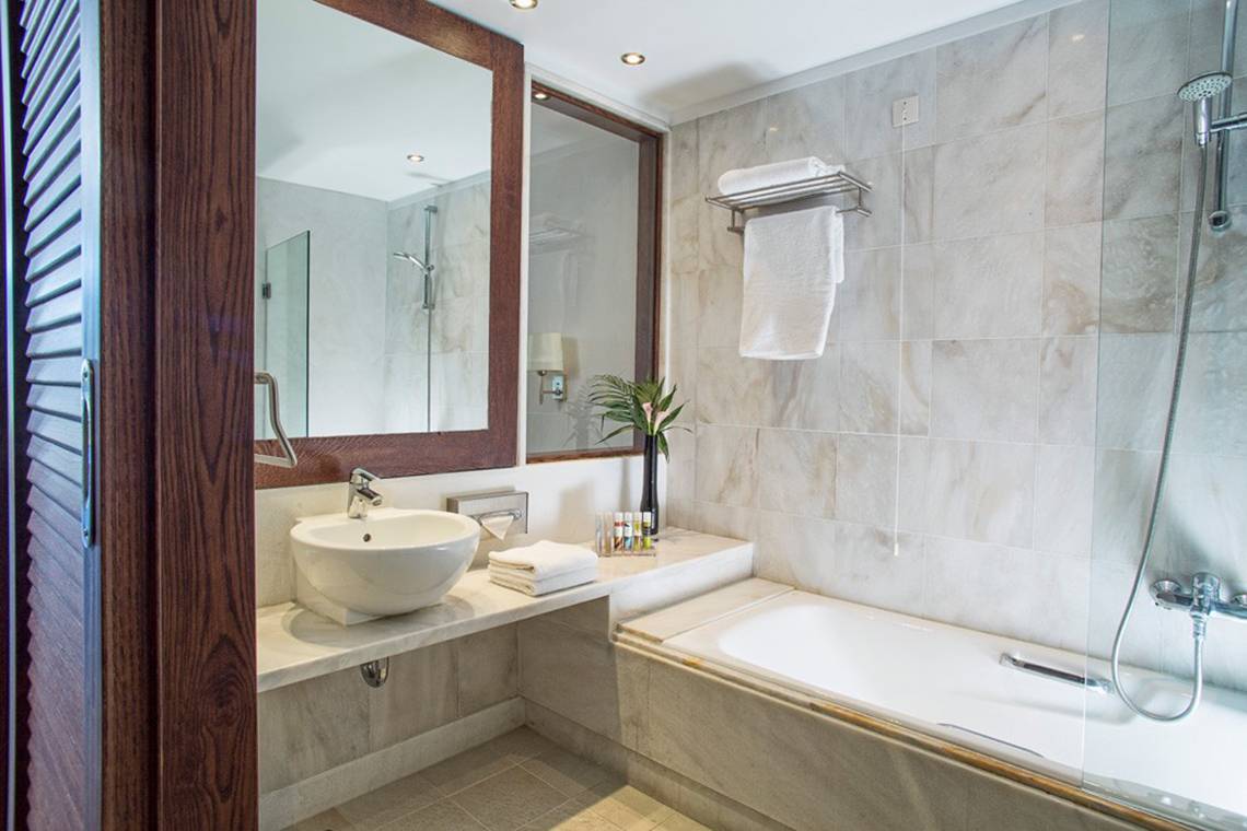 Badezimmer im Kontokali Bay Resort & Spa mit Badewanne, Spiegel und Waschbecken.