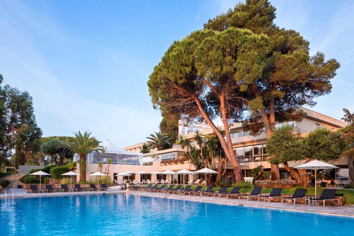 Poolbereich des Kontokali Bay Resort & Spa mit Sonnenliegen und Schirmen.