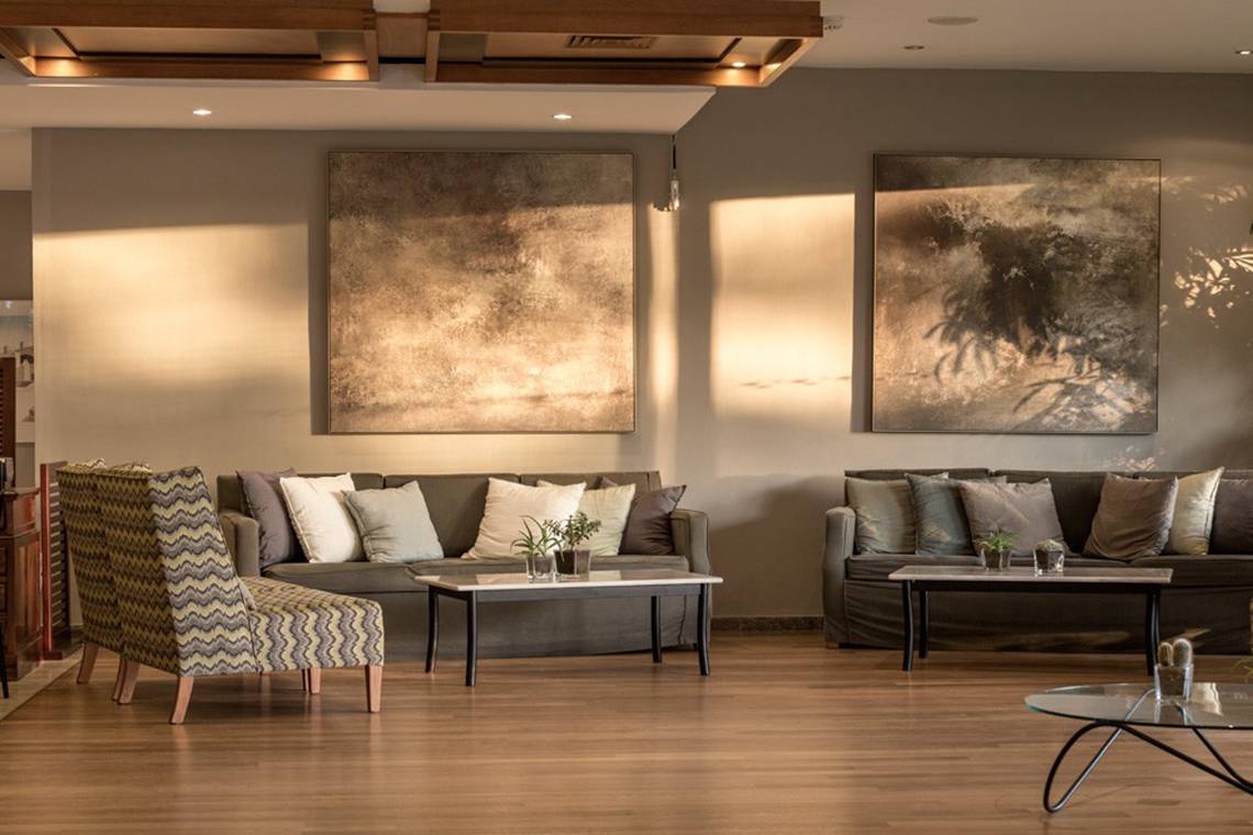 Lobby des Kontokali Bay Resort & Spa mit Sofas, Tischen und Gemälden an der Wand.