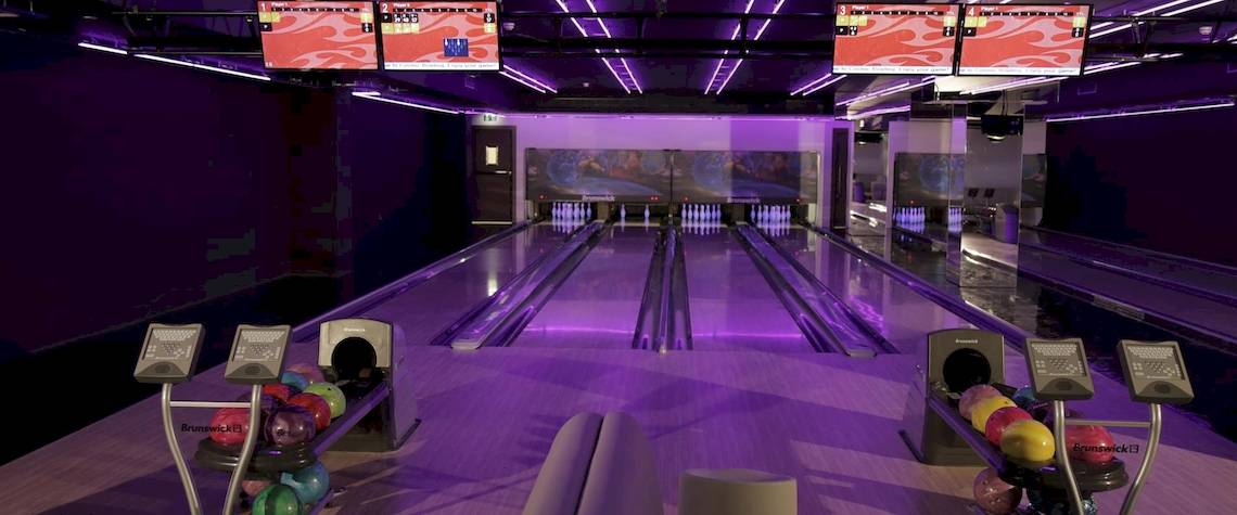 Kempinski Hotel Muscat Bowlinghalle mit Bowlingbahnen und lila Beleuchtung.