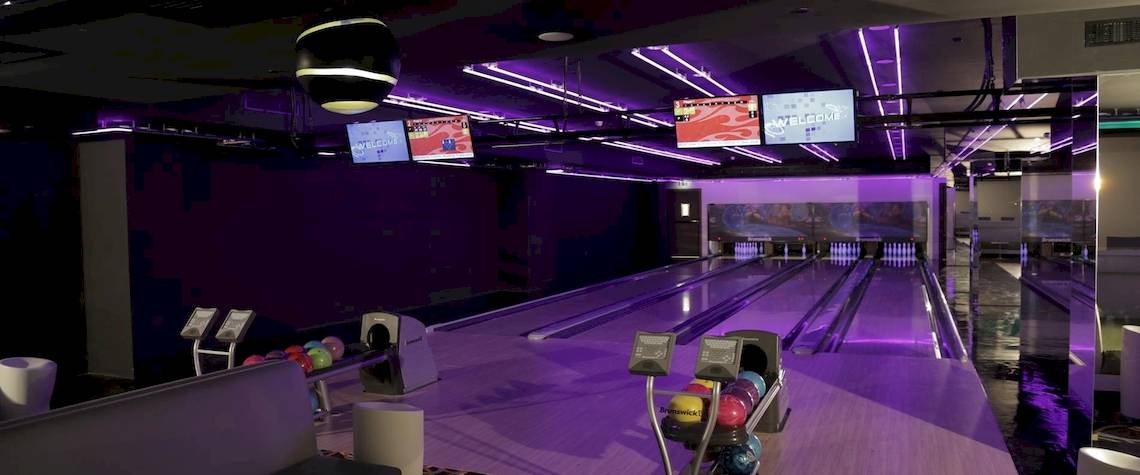 Bowlinghalle im Kempinski Hotel Muscat mit violetten Lichtern und Bowlingbahnen