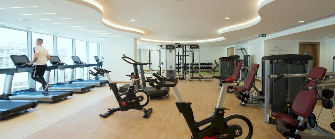 Fitnesscenter im Kempinski Hotel Muscat mit einem Mann, der auf einem Laufband läuft.