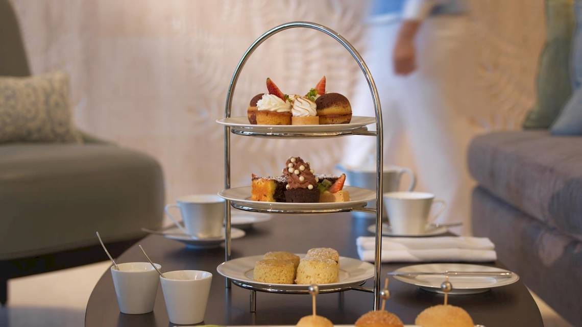 Empfangsbereich des Kempinski Hotels Muscat mit einer Auswahl an Desserts auf einem dreistöckigen Serviertablett.