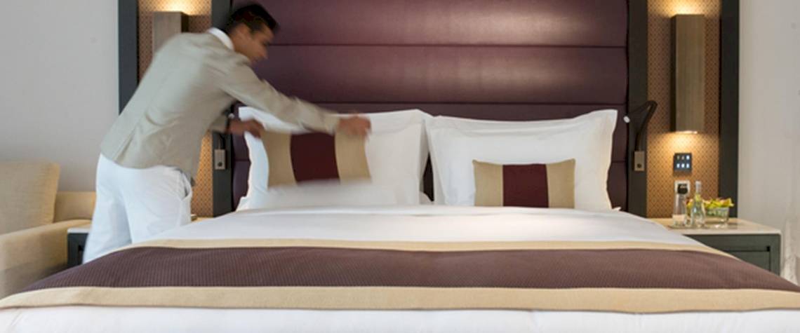 Ein Mitarbeiter des Kempinski Hotel Muscat macht das Bett in einem Gästezimmer.