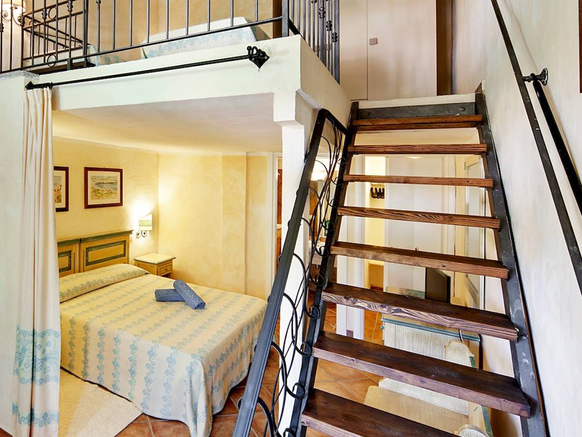 Doppelbett-Zimmer mit Aufzug im Hotel Colonna Du Golf mit hellem Dekor, Holztreppe und Balkon.