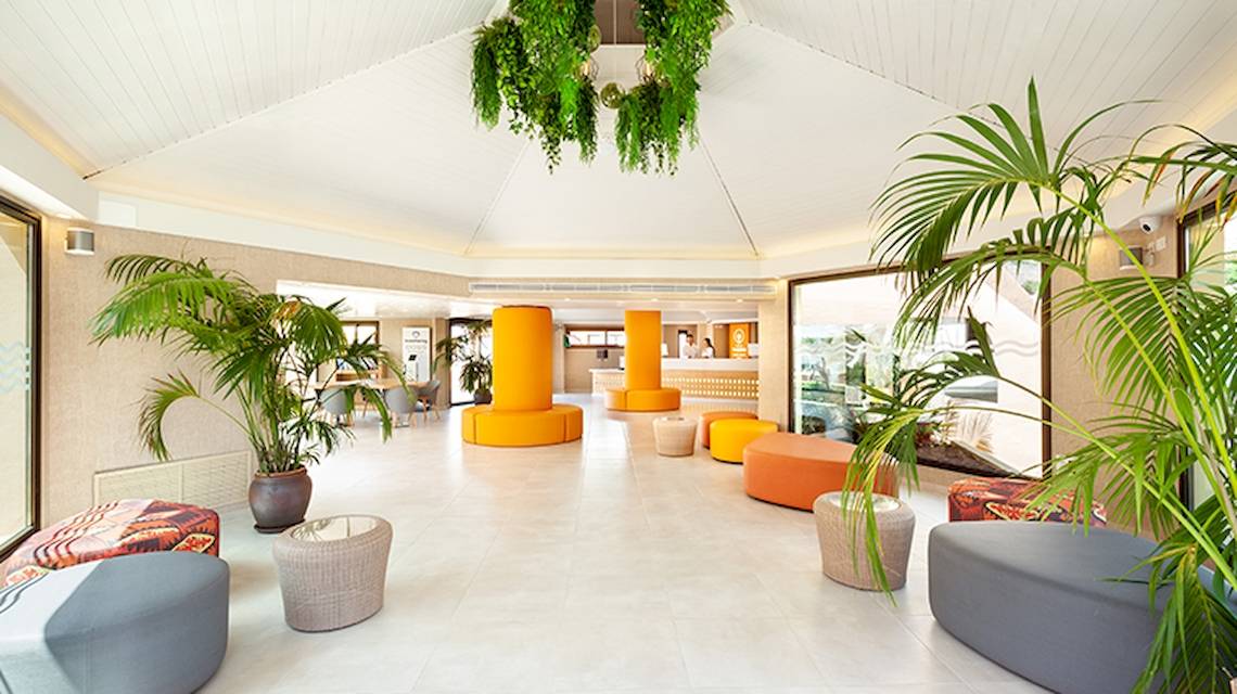 Lobby des Tagoro Family & Fun Costa Adeje Hotels mit modernen Möbeln, Pflanzen und Empfangstresen.