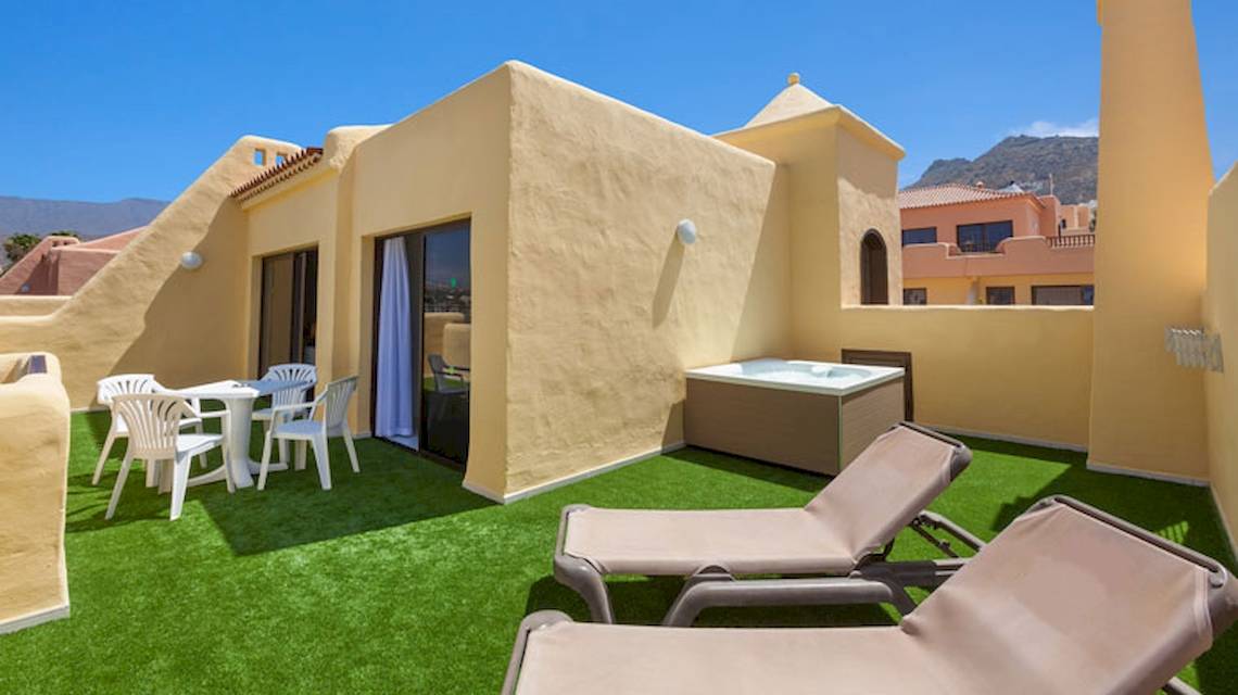 Dachterrasse des Tagoro Family & Fun Costa Adeje mit Whirlpool, Tischen und Stühlen.