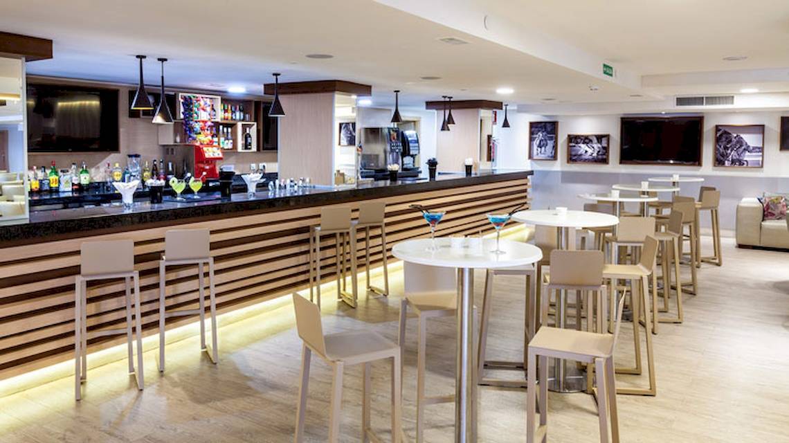Barbereich im Tagoro Family & Fun Costa Adeje Hotel mit gepolsterten Stühlen und runden Tischen.