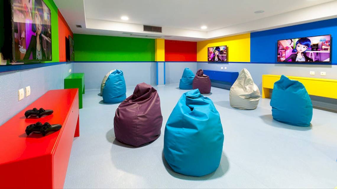 Spielzimmer im Tagoro Family & Fun Costa Adeje mit bunten Wänden, mehreren Fernsehgeräten und bunten Beanbags.