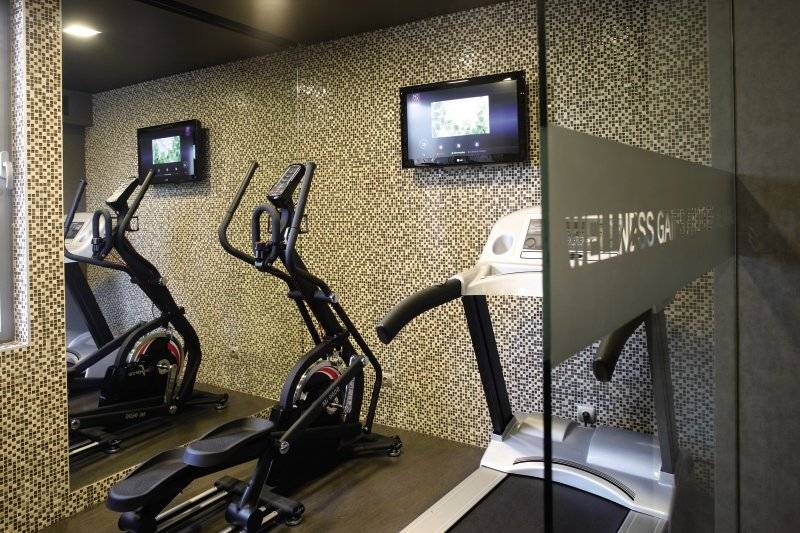 Fitnessraum im Neya Lisboa Hotel mit Laufband, Crosstrainern und Fernsehern an der Wand.