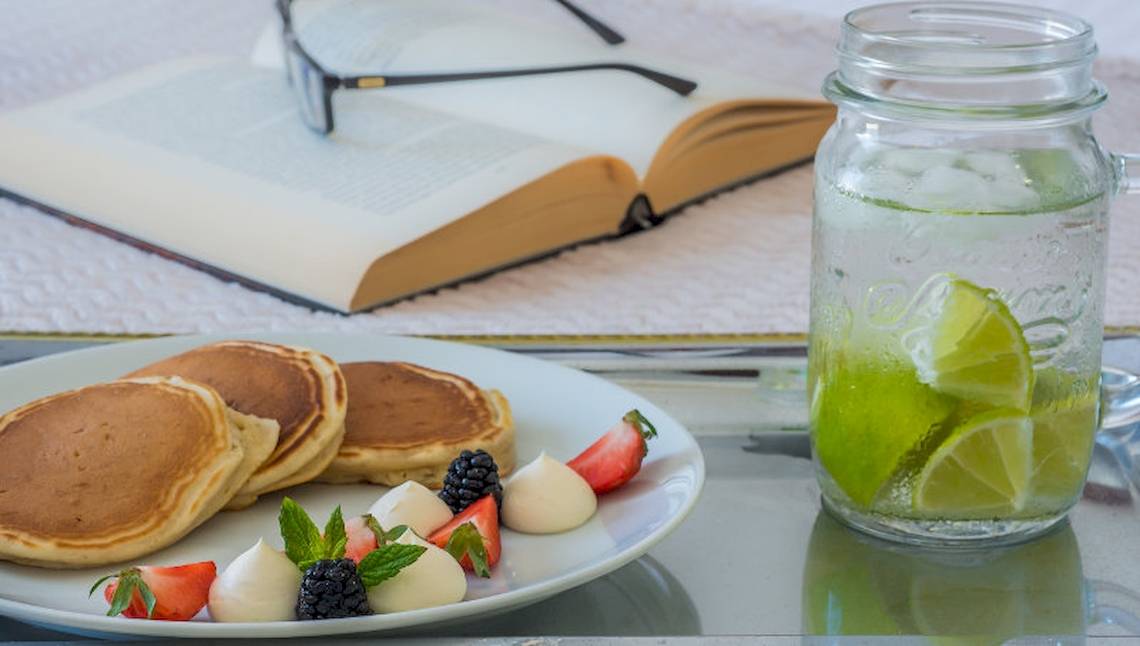 Ein Teller mit Pfannkuchen, Früchten und einem Glas Wasser mit Zitronenscheiben.