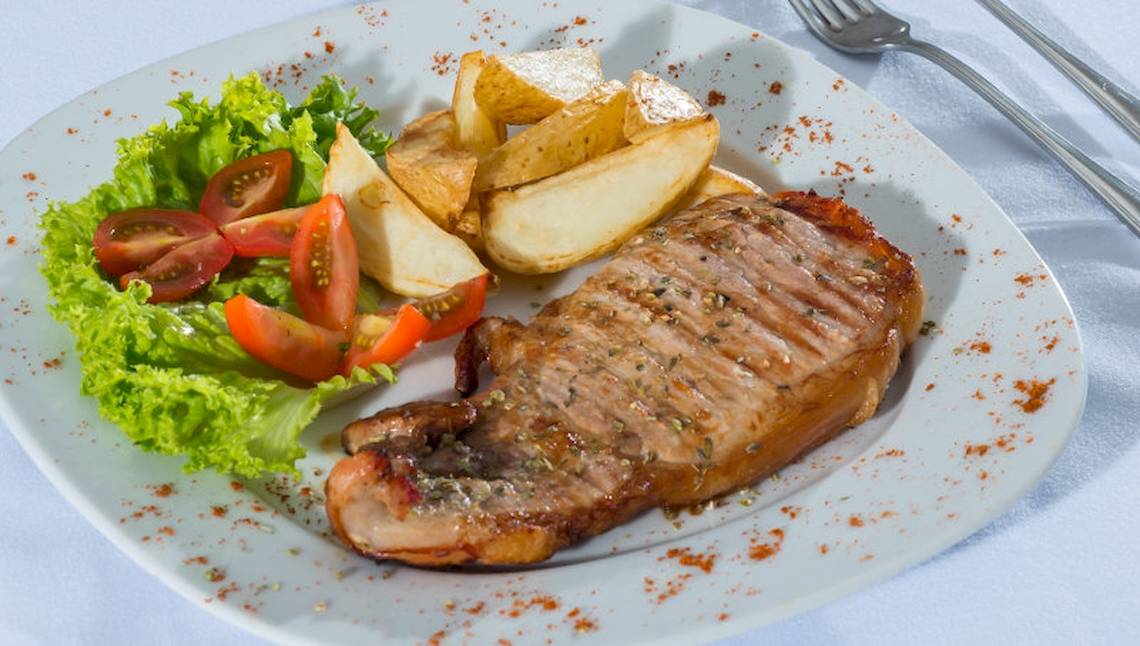 Gegrilltes Steak mit Gemüse und Kartoffel auf einem weißen Teller.