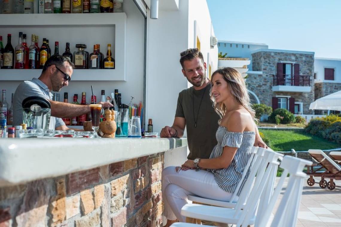 Besucher sitzen an der Bar des Naxos Palace Hotels und genießen Getränke.