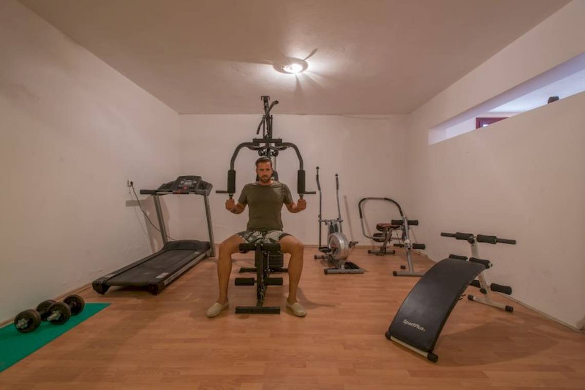 Fitnessraum im Naxos Palast Hotel mit einem Mann, der ein Liegestützgerät benutzt.